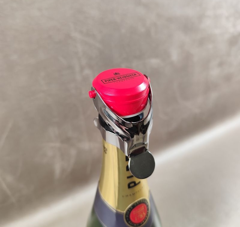 Custom champagne stopper printed with a champagne house logo, fitted on a bottle